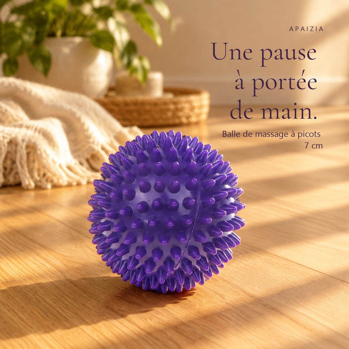 Balle de massage à picots violette posée sur un parquet ensoleillé